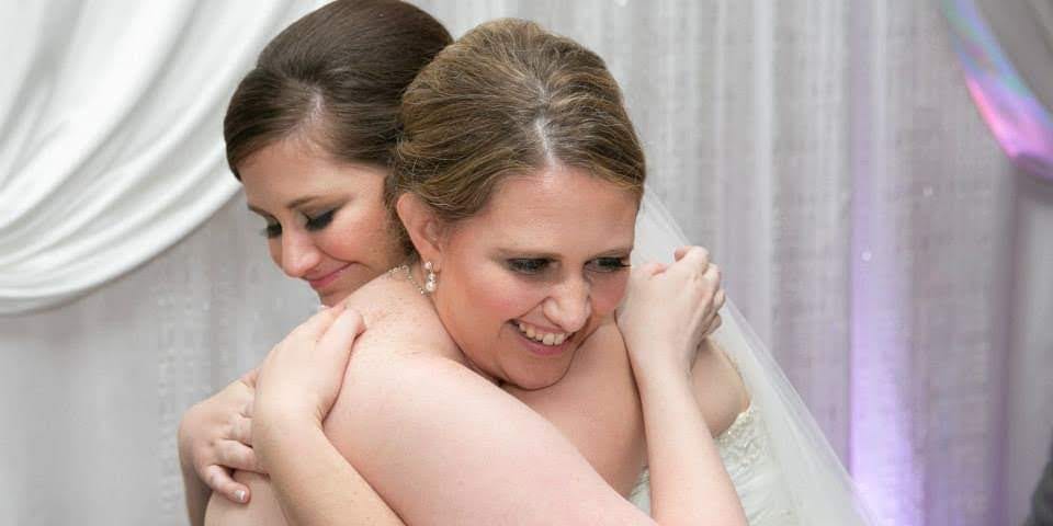 2 daughters hugging on a wedding day
