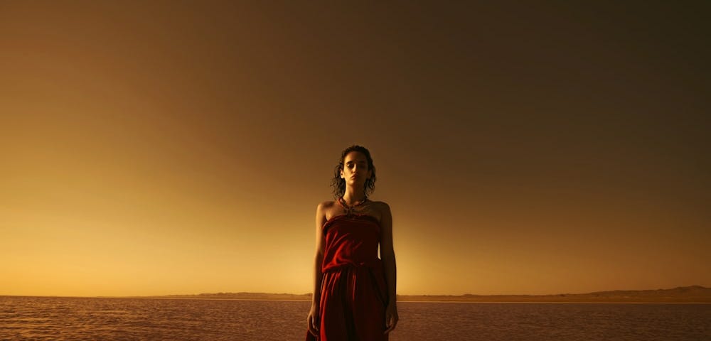 Young woman in a red gown in dark desert landscape