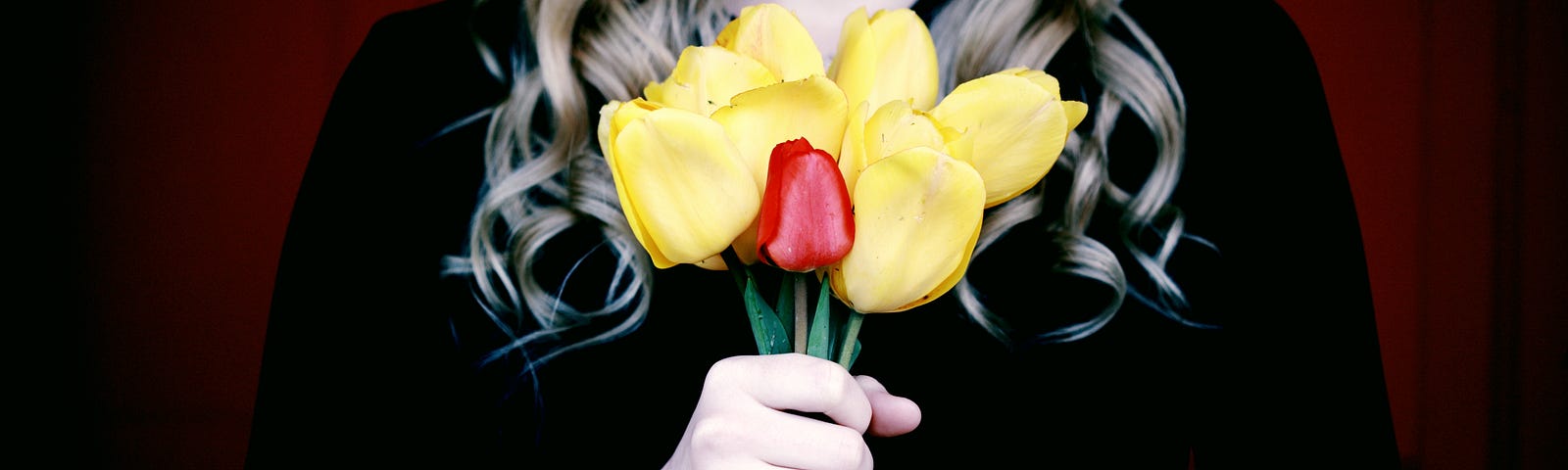 blond woman holding a bunch of yellow and red tulips