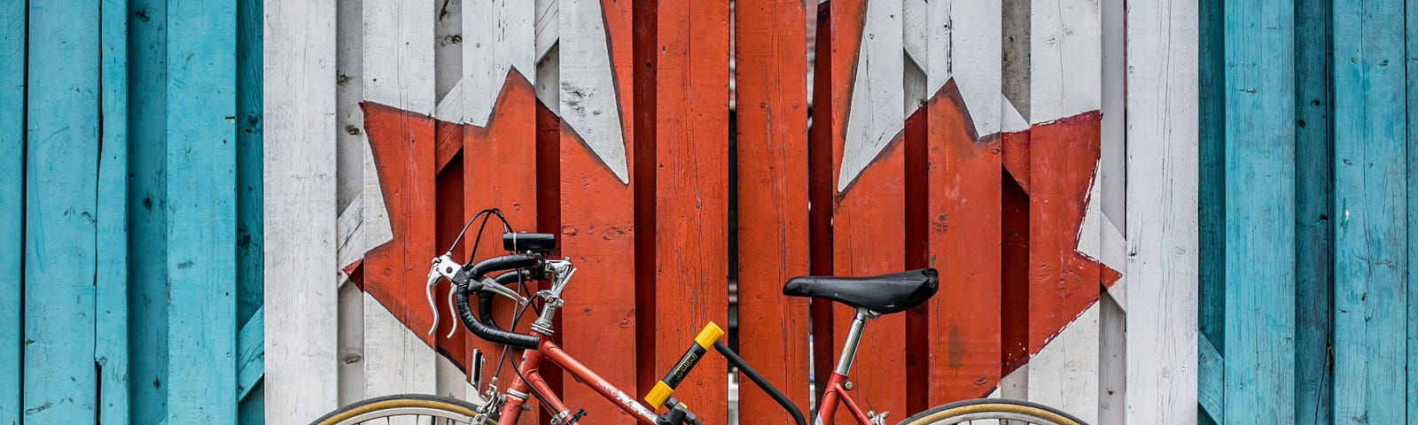A bike leaning up against a wall with a painted maple leaf