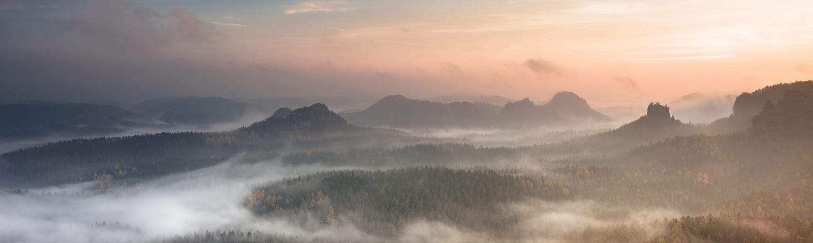 Fog wraps through a hilly landscape.