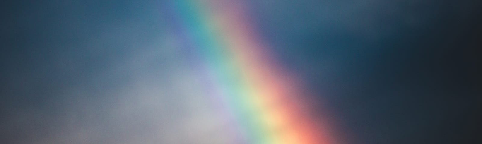 Rainbow over mountain, sky is dark a bit of black and dark blue