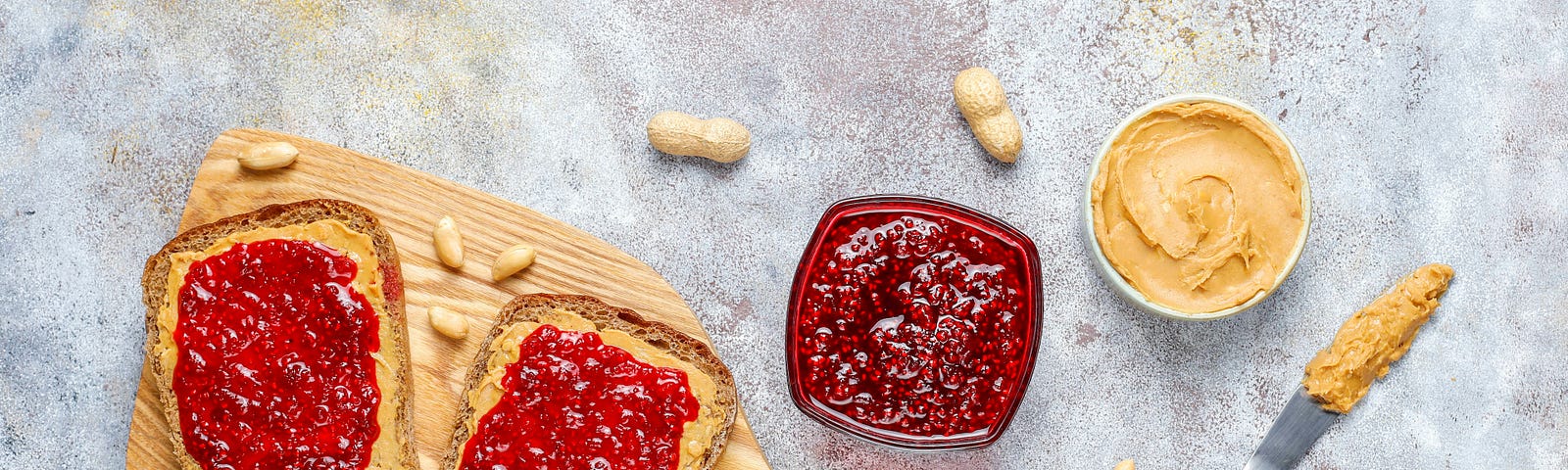 deconstructed pb&j sandwich on a cutting board next to jars of peanut butter and jelly