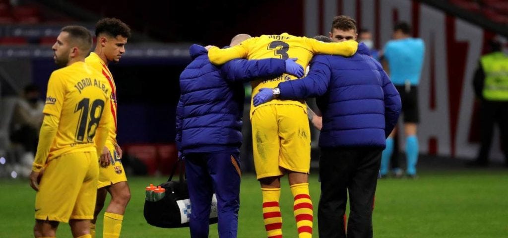FC Barcelona defender Gerard Piqué is helped off the pitch after suffering an ACL injury.