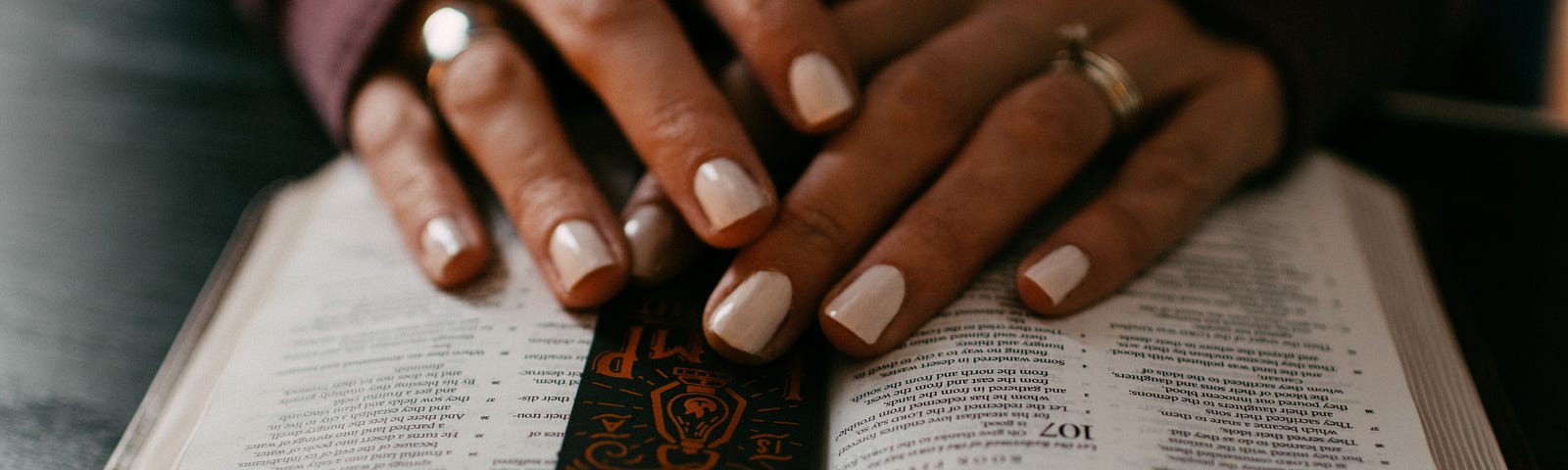 Woman’s hands laying on an open Bible. Prayer.