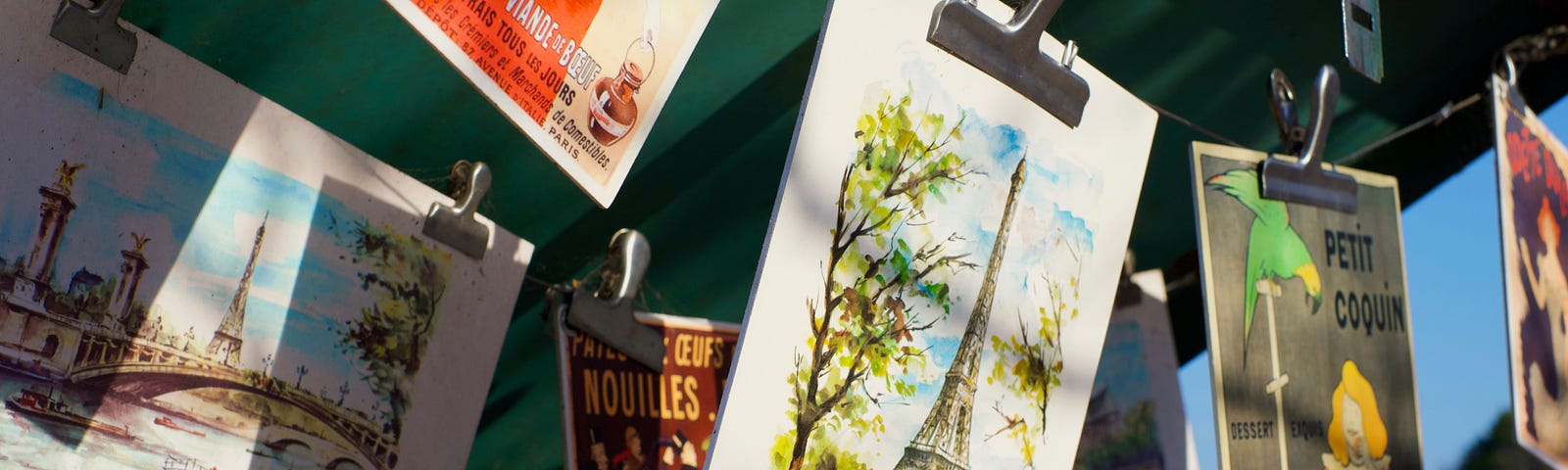 Postcards hanging from a clothesline. They show motifs from Paris.