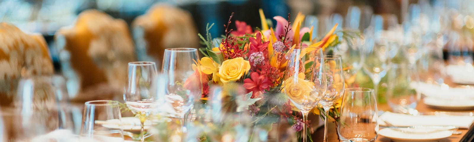 A large table that can seat several guests is well laid out with utensils and glassware