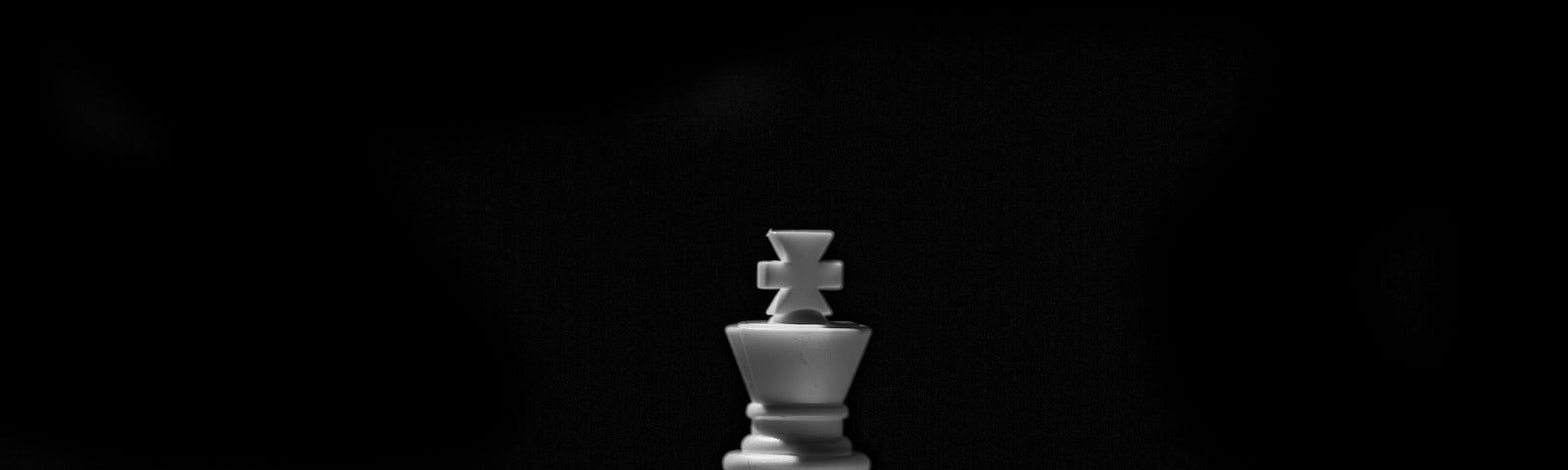 Lone chess king in spotlight, on dark background