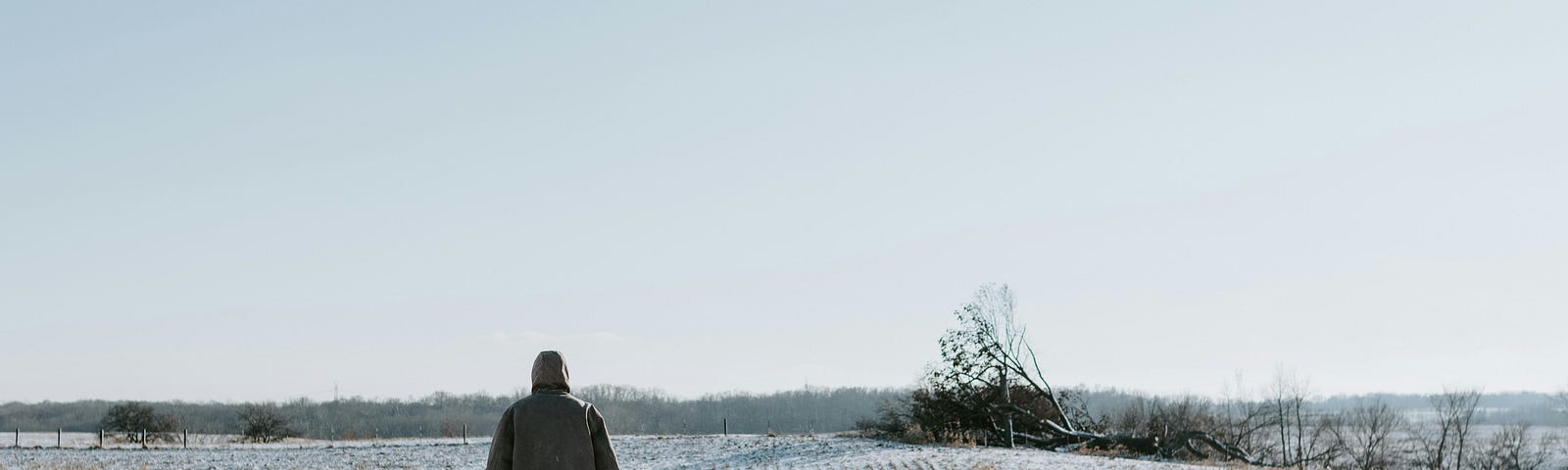 A man and a small child walk on a snowy field in winter.