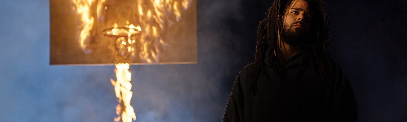 Jermaine Cole standing in front of a burning basketball hoop