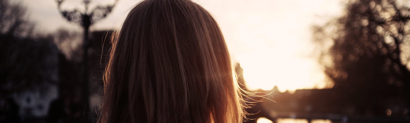 A woman looking away from the camera, out towards the setting sun