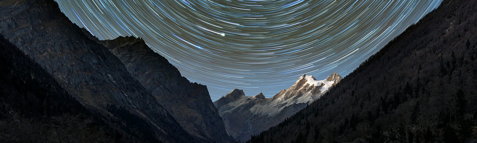 Spiraling stars in a dark night scene in the mountains