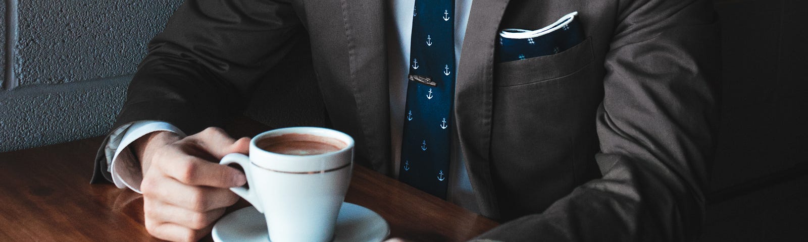 Businessman in tweed coat and polo tie drinking dark coffee