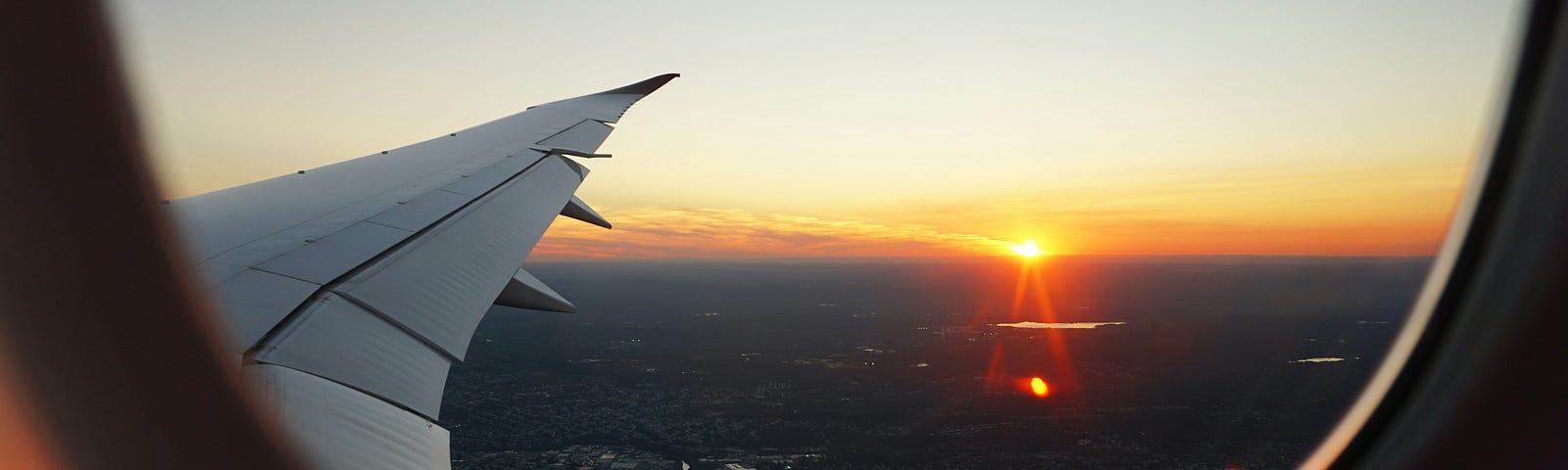 Image of the sun setting through an airplane window