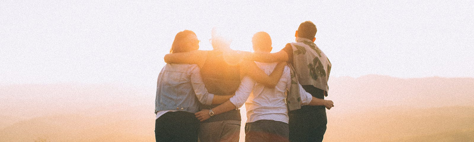 Four friends supporting each other with arms draped around their shoulders