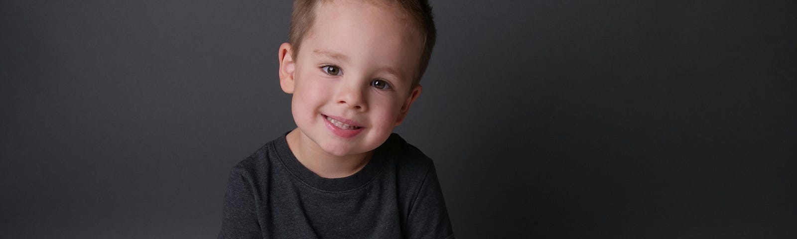 Photo of small boy looking at the camera with an angelic smile on his face.