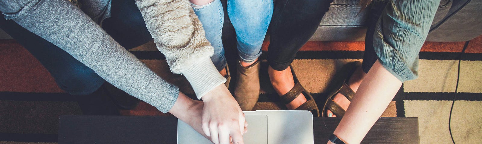 Three women sitting together and pointing at a laptop