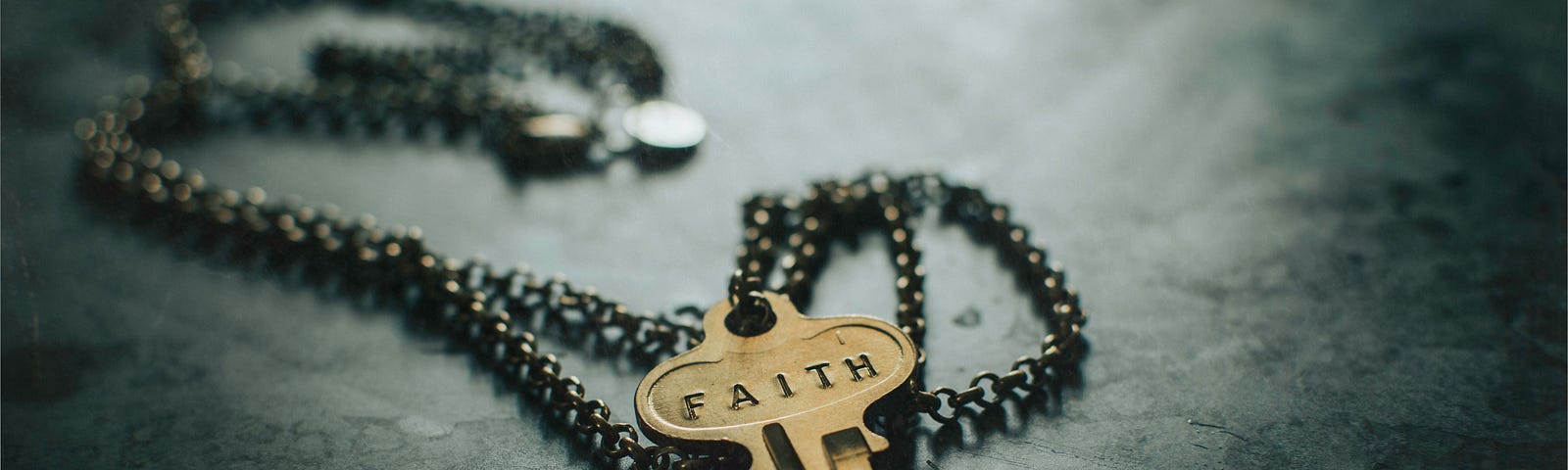 Photo of a key with the word “Faith” engraved on it, attached to a necklace.