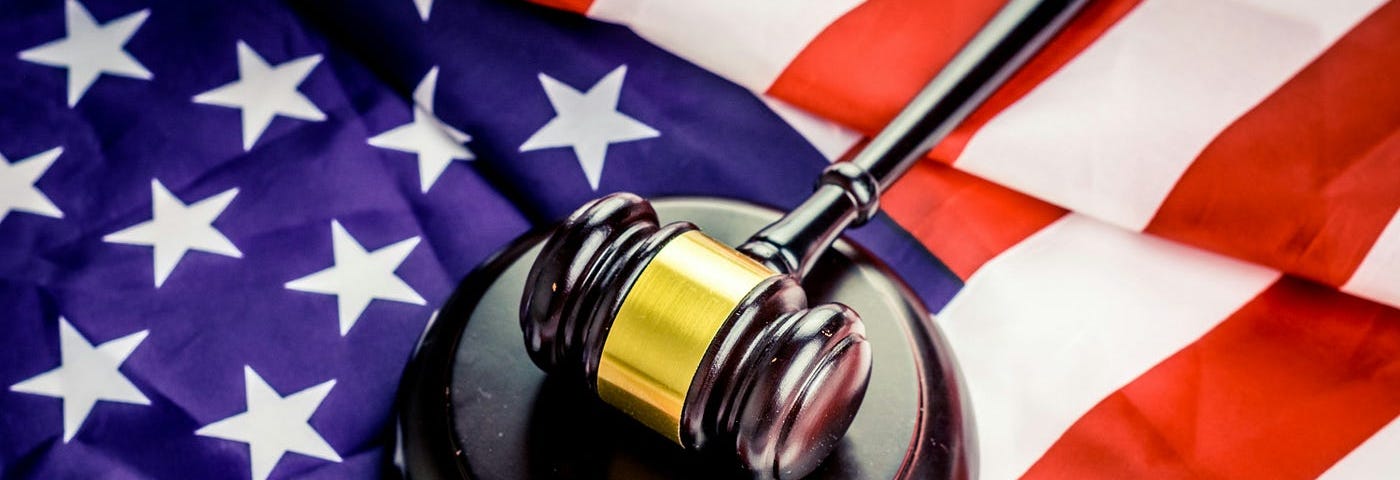 A judge’s gavel and hammer resting on top of the red, white and blue flag of the United States of America.