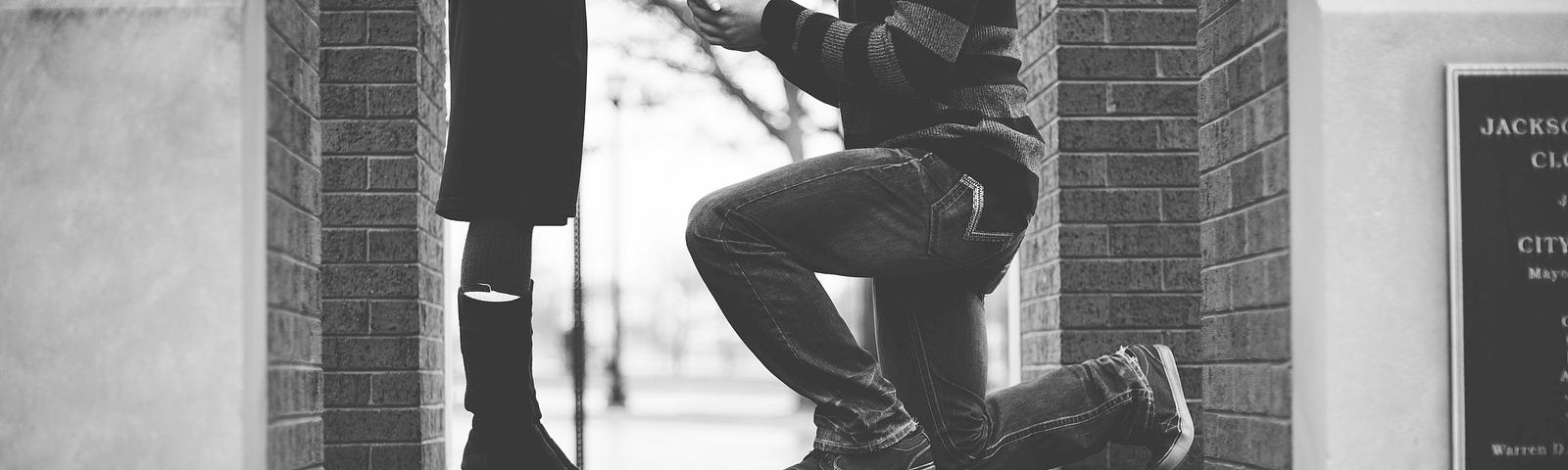 Man on bended knee proposing to woman