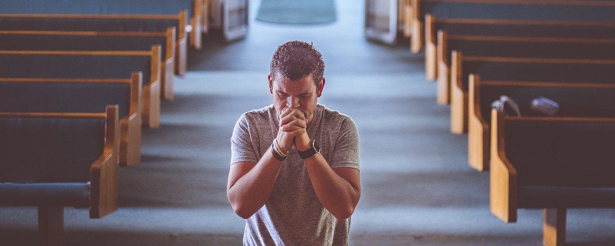 Man praying kneeling at the altar in a church