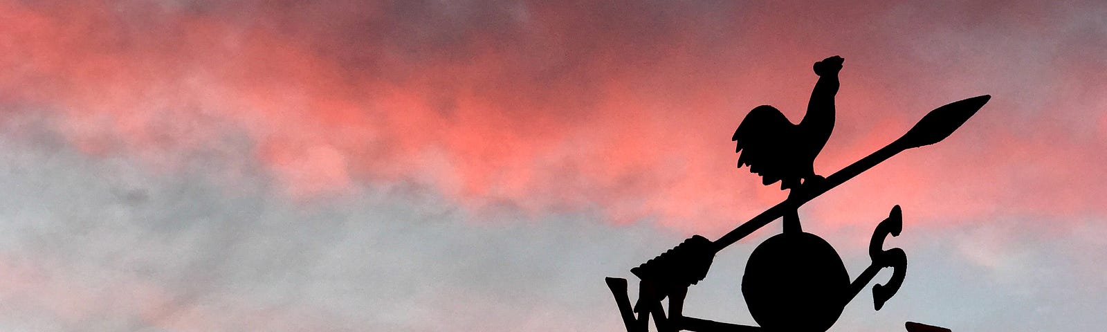 A weather vane attempts to point the way for us against a backdrop of sunset sky.