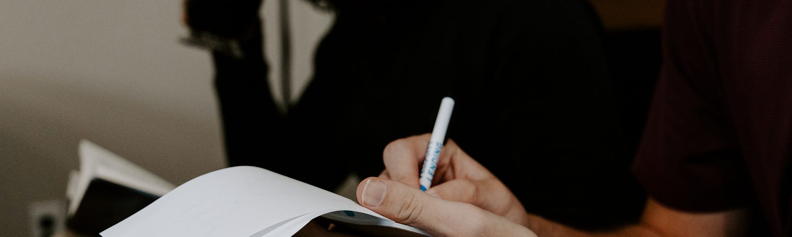 A person writing new ideas on a notepad