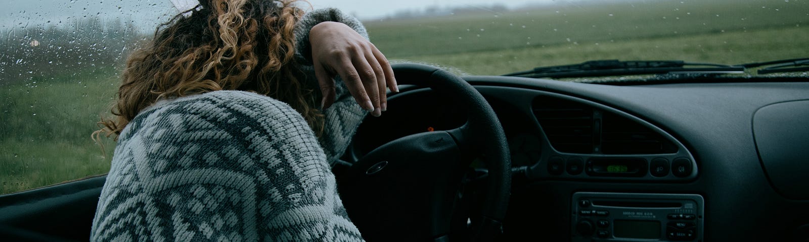 Women in car with her head on the steering wheel.