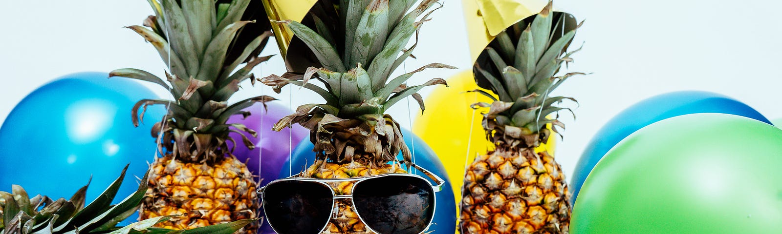 Pineapples with sunglasses on and balloons