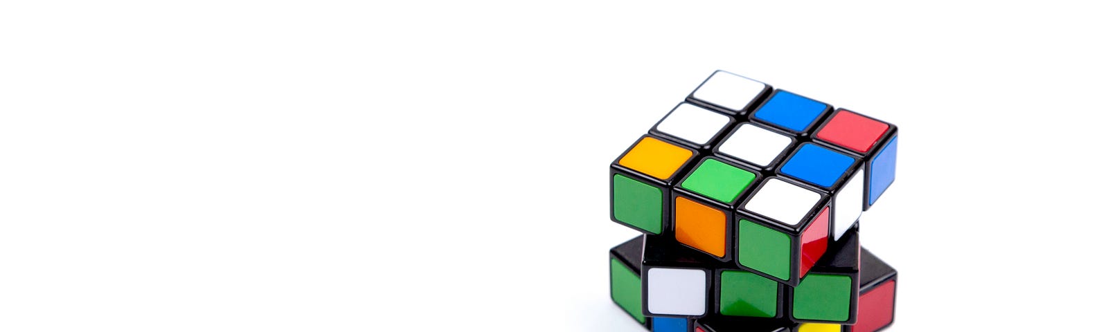 Rubik’s cube, partially open, sits on the right side of an otherwise empty image.