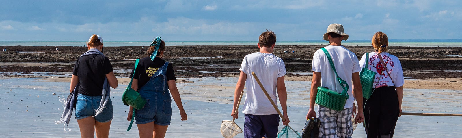 A group of young adults collecting crabs at low tide at a beach