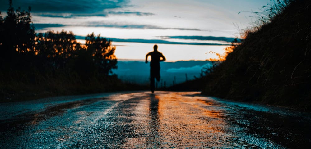 Silhouette of a person running on a road