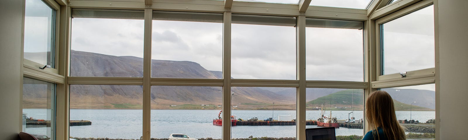 Woman working productively on a laptop in front of a window overlooking a lake.