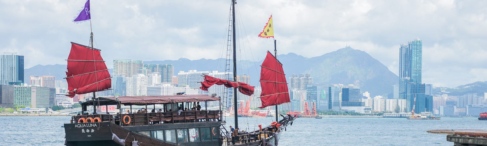 small Chinese boat with red sails and colorful flags