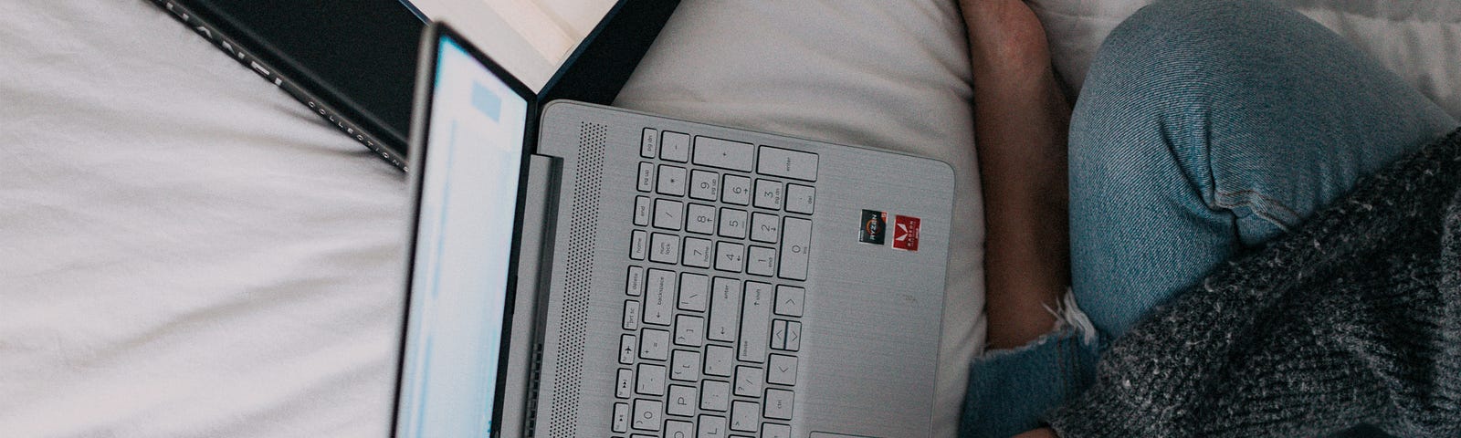 A girl is sitting on the bed and studing/learning/working.