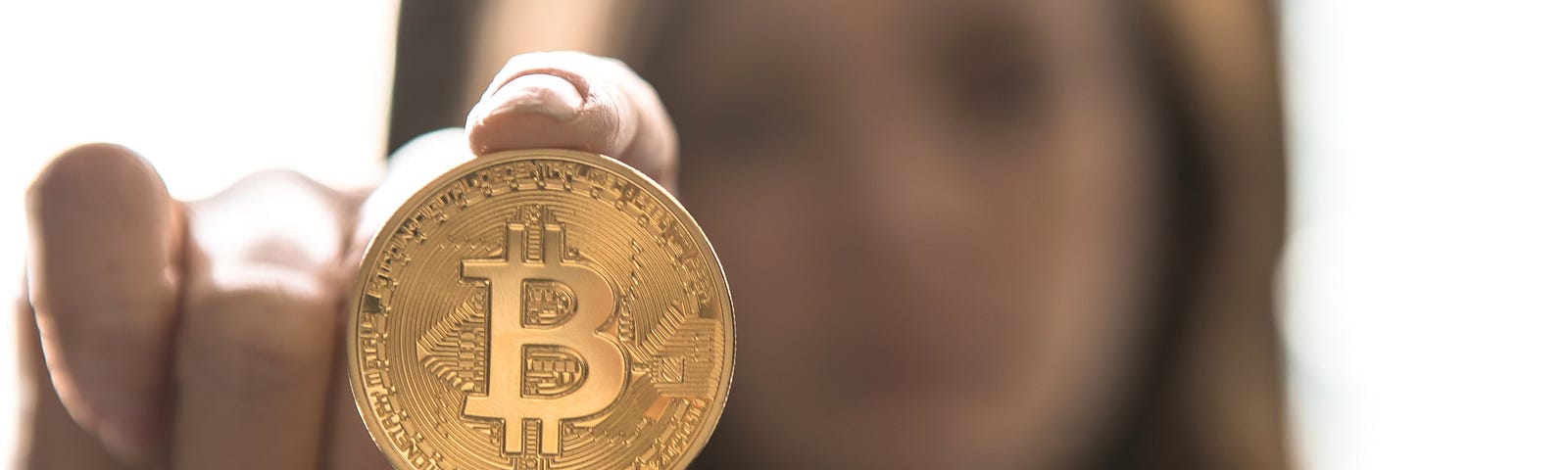 Woman holding a bitcoin token in front of her face