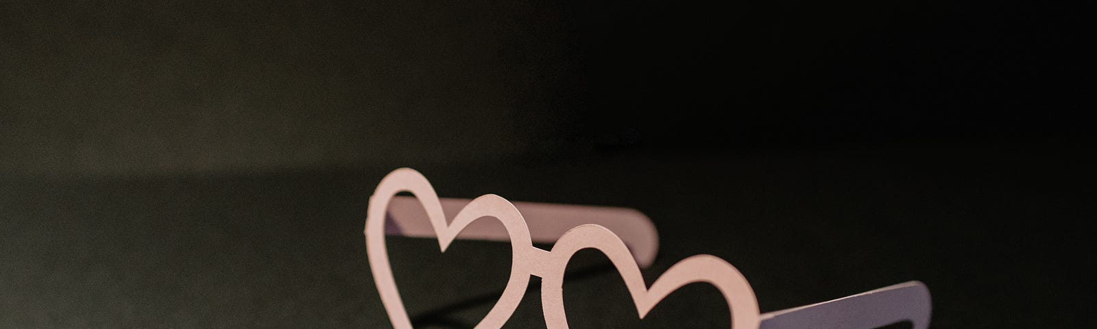 Pink heart shaped glasses on black background