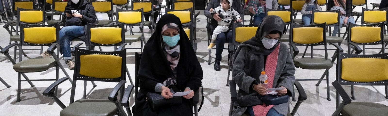 Two women wait to receive a COVID-19 vaccination at the Iran Mall shopping center in western Tehran, Iran, February 5, 2022. Photo by Morteza Nikoubazl/Reuters