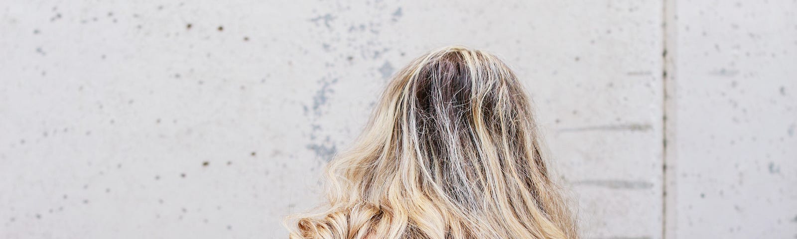 Person with long, blonde hair photographed wearing jeans and facing away from the camera.