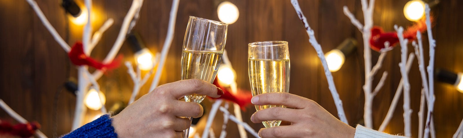 This photos shows two hands clinking to glasses of champagne in a toast.