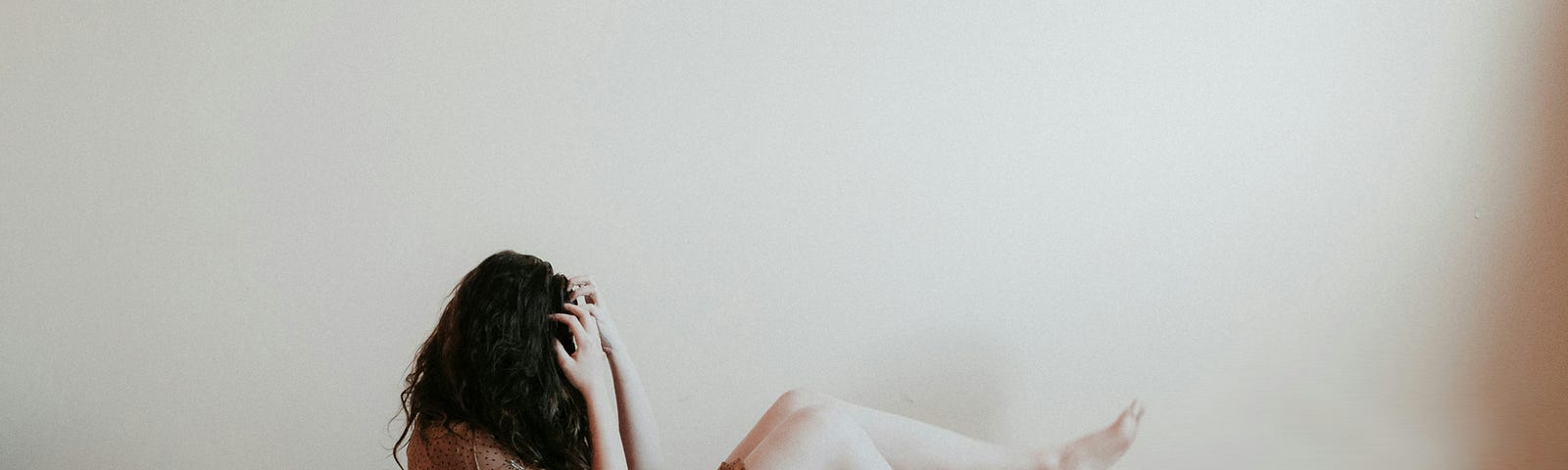 woman in anguish sitting on the ground covering her face with her hair and hands, grief, loss,