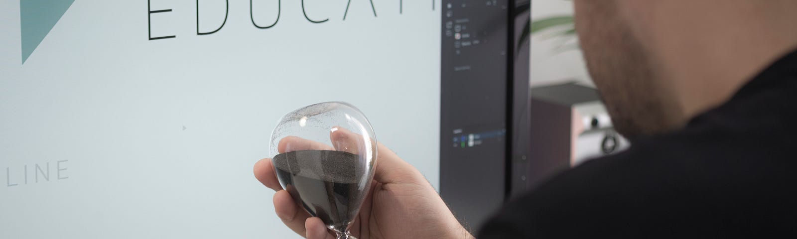 A man holding hourglass in his hand to set time for his work