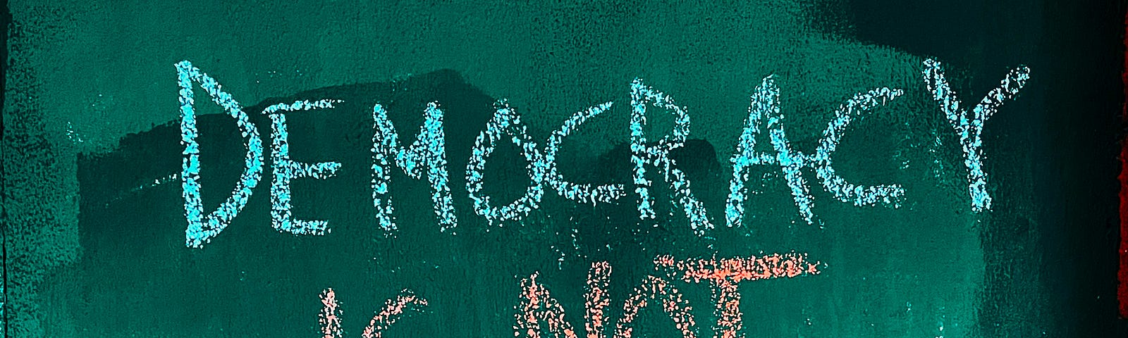 A message written in chalk: Democracy is not a spectator sport.