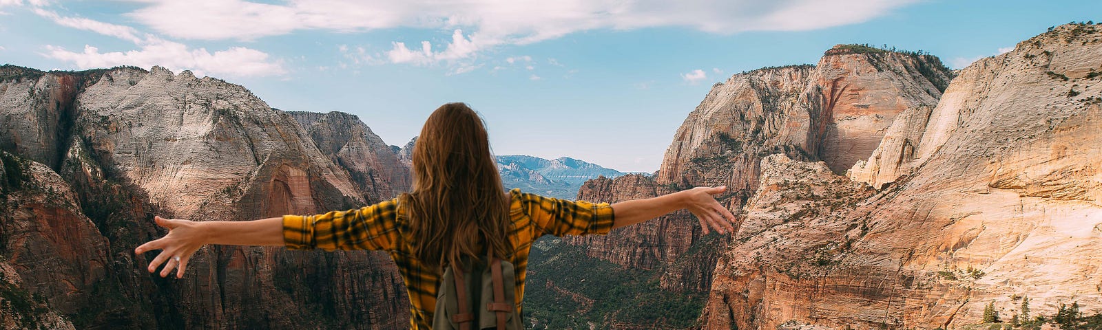 woman overlooking canyon with arms spread wide, representing a life of freedom