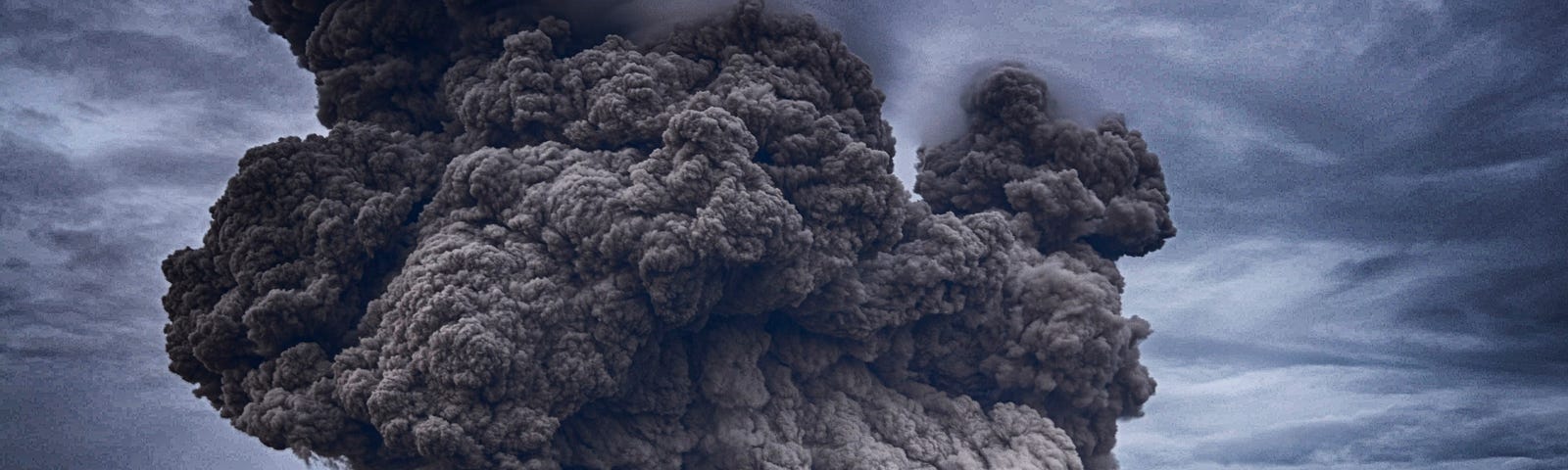 Volcano spews ash under darkened sky.