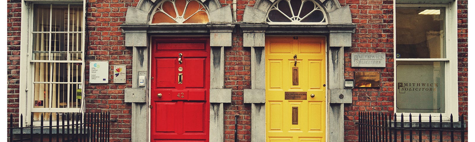 A shot of two front doors side by side, one red and one yellow