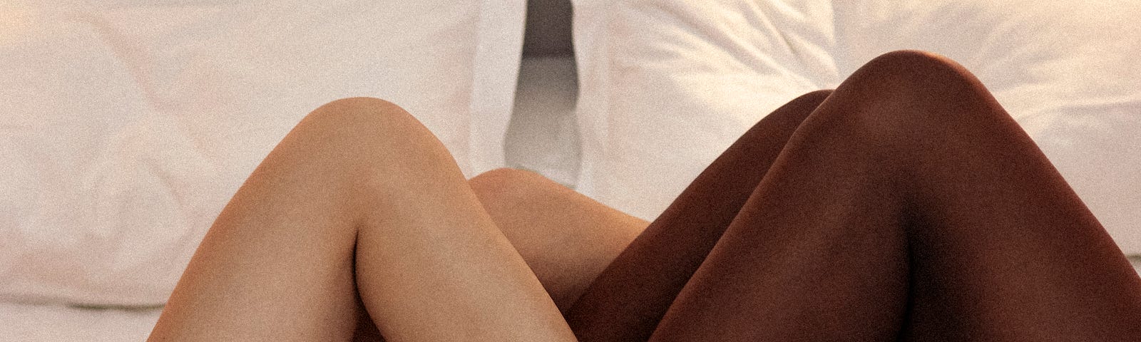 The intertwined legs of two sexy women in bed