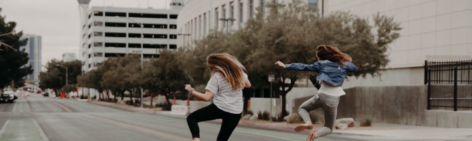 Two people jumping up clicking their heels in the middle of a city street.