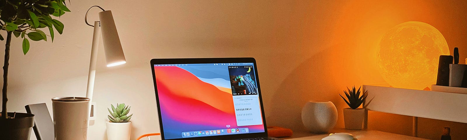 This image depicts a book, a lamp, and a laptop on top of a desk.