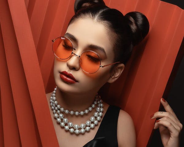 Woman in sunglasses and pearl necklace looking off camera with a thoughtful and confident look on her face